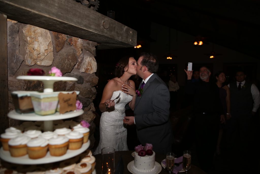 Rustic fall wedding at Calamigos Ranch, bride and groom cake cutting kiss, cupcake tower