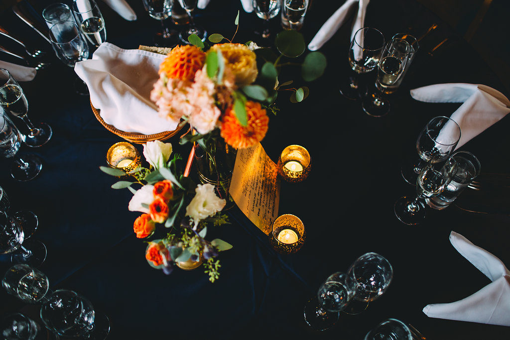 A garden wedding at Mermaid Mountain Inn, centerpieces with orange flowers in vintage gold vases