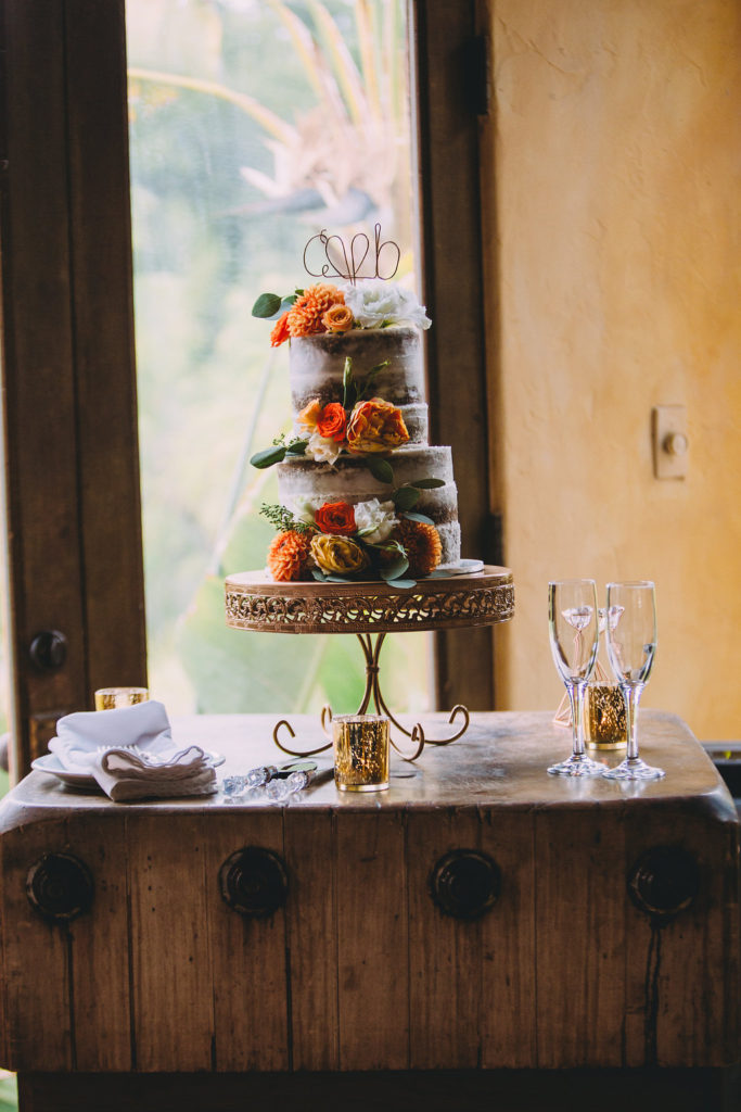 A garden wedding at Mermaid Mountain Inn, cake with orange flowers on vintage cake stand