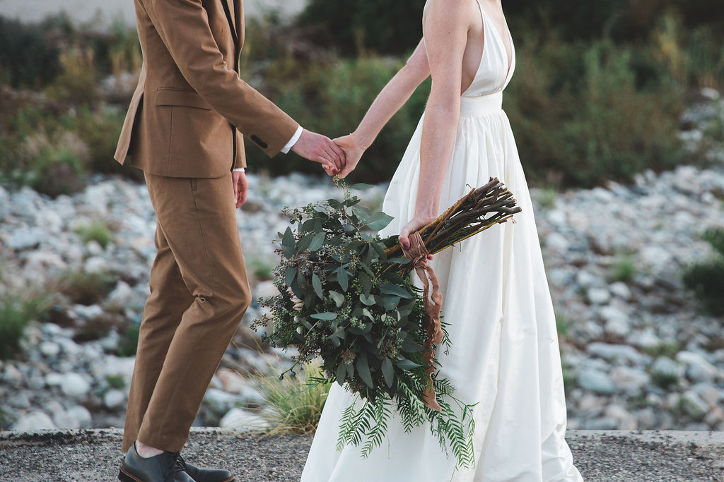 Unique wedding at Elysian LA, bride and groom portrait with groom in brown suit and glasses, bride with simple white dress and red lipstick, mixed greenery bridal bouquet