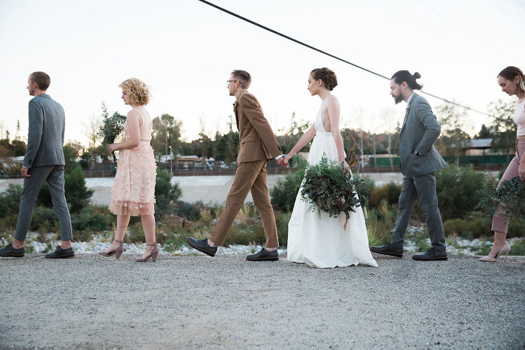 Unique wedding at Elysian LA, bride and groom portrait with groom in brown suit and glasses, bride with simple white dress and red lipstick, wedding party with mixed blush bridesmaid dresses, grey groomsmen suits, brown groom suit with glasses and simple white wedding dress, mixed greenery bridal bouquet