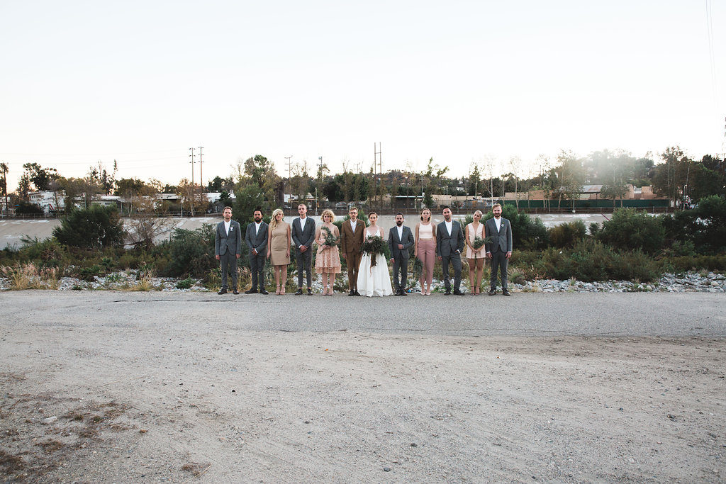 Unique wedding at Elysian LA, bride and groom portrait with groom in brown suit and glasses, bride with simple white dress and red lipstick, wedding party with mixed blush bridesmaid dresses, grey groomsmen suits, brown groom suit with glasses and simple white wedding dress