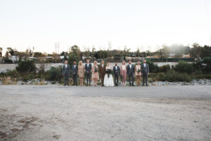 Unique wedding at Elysian LA, bride and groom portrait with groom in brown suit and glasses, bride with simple white dress and red lipstick, wedding party with mixed blush bridesmaid dresses, grey groomsmen suits, brown groom suit with glasses and simple white wedding dress