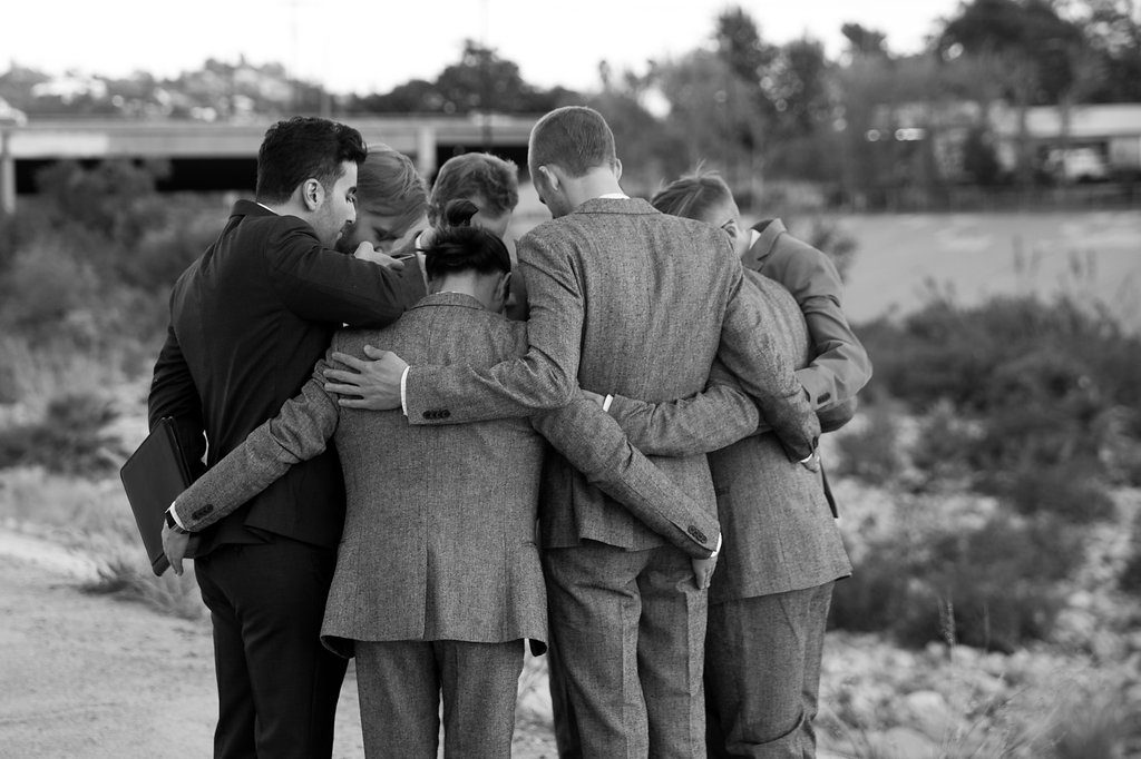 Unique wedding at Elysian LA, bride and groom portrait with groom in brown suit and glasses, bride with simple white dress and red lipstick, groomsmen and groom prayer