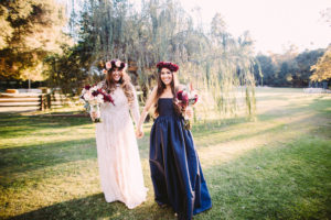 Fall Wedding at Calamigos Ranch, bride and bridesmaid wearing navy dress with maroon and blush floral crowns and bouquets