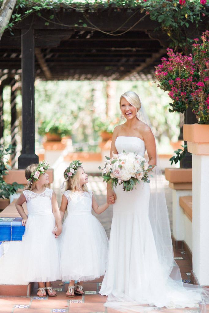 Rancho Las Lomas wedding, bride wearing strapless wedding dress and chapel veil with flower girls wearing white dresses