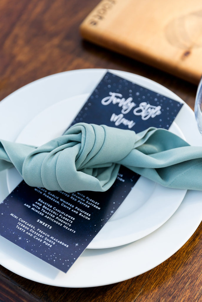 green knotted napkin with a navy blue dinner menu for a wedding reception