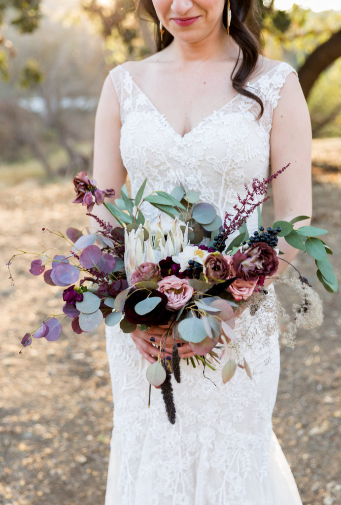 White protea bridal bouquet with greenery and burgundy flowers