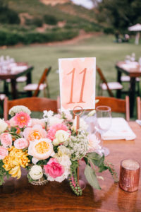 Pink and blush watercolored table numbers with pink, yellow and white wildflower wedding centerpieces