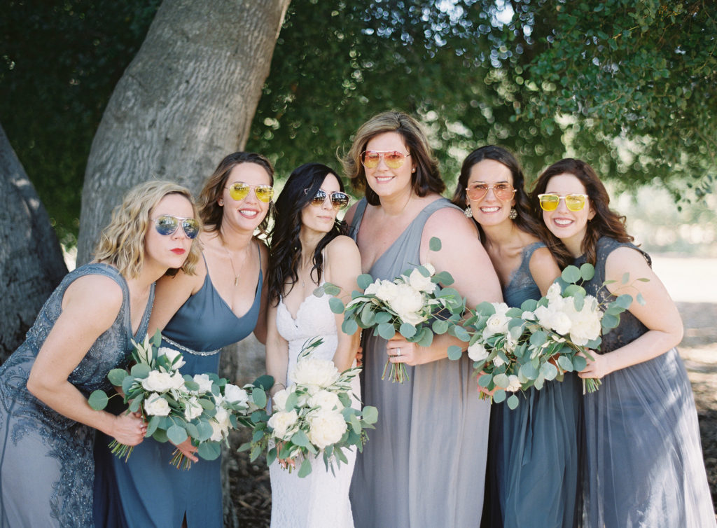 Grey and blue bridesmaids dresses and white floral bouquets at Triunfo Creek Vineyards with fun sunglasses
