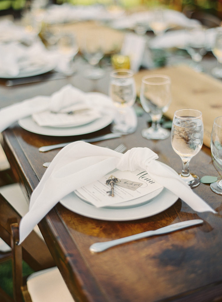 White napkins tied in a knot on white plates on a farm table