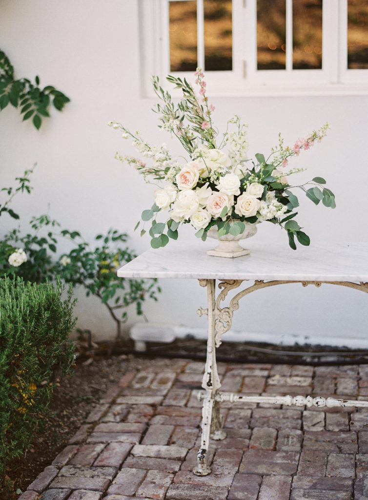 White floral centerpiece with blush florals and lots of greenery at a Vineyard