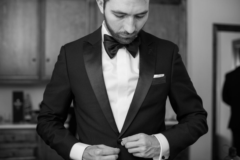 groom getting ready with black tuxedo and black bowtie
