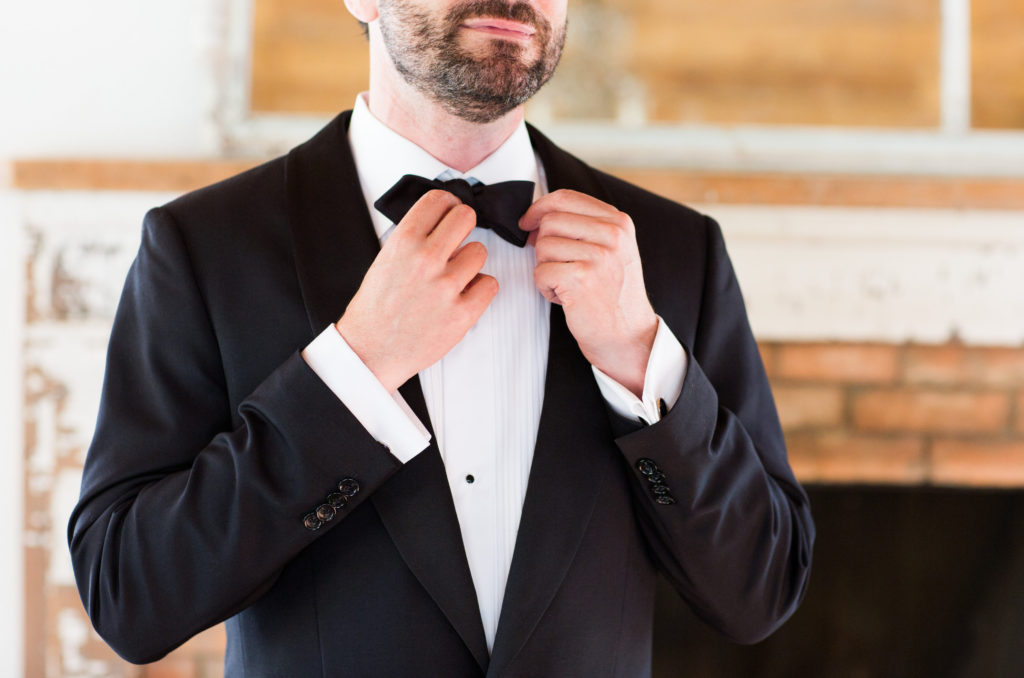 Royal Inspired Vineyard Wedding at Triunfo Creek Vineyards, groom getting ready and trying bowtie on black tuxedo