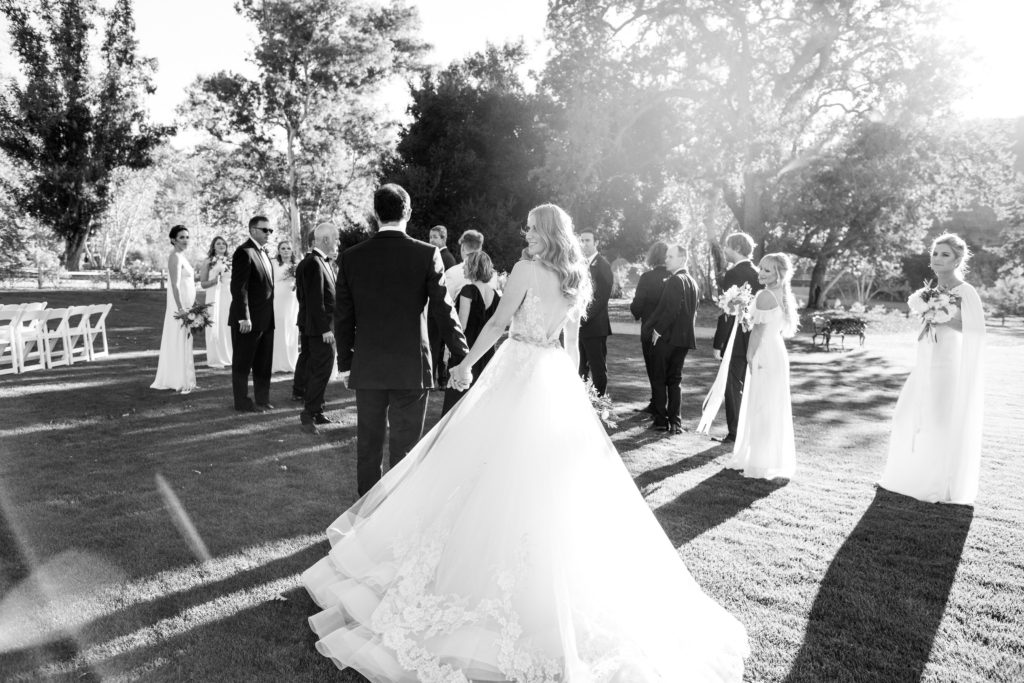Royal Inspired Vineyard Wedding at Triunfo Creek Vineyards, wedding party photo with white bridesmaid dresses and black groomsmen suits