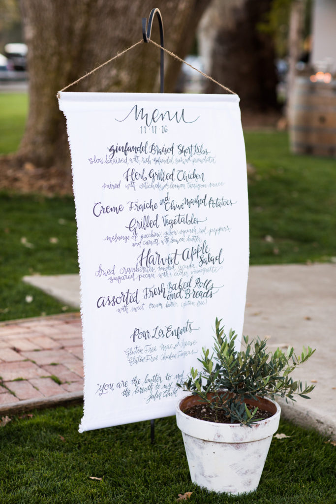 Royal Inspired Vineyard Wedding at Triunfo Creek Vineyards, outdoor wedding reception menu on a banner