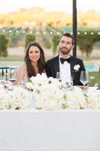 Sogno del fiore wedding reception in Santa Ynez winery, bride and groom toasts, all white flower centerpieces