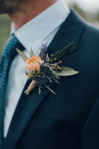 A desert wedding in Ojai at Red Tail Ranch, groom in navy suit with ranunculus boutonniere
