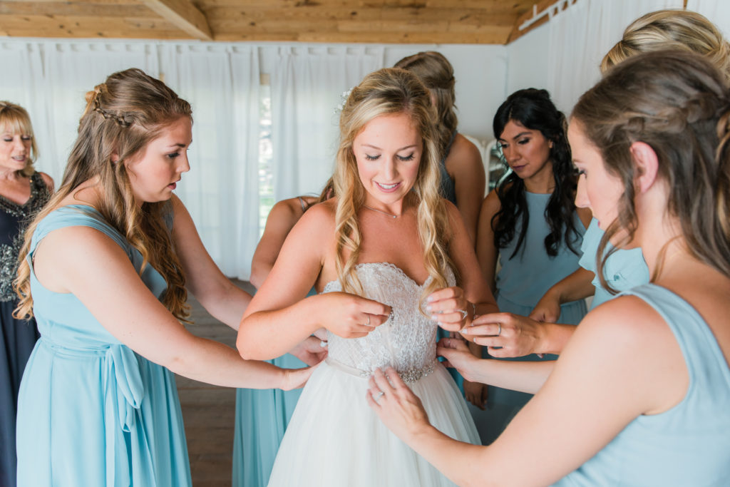Elegant fall wedding at Triunfo Creek Vineyards, bride getting ready with help from bridesmaids in blue dresses