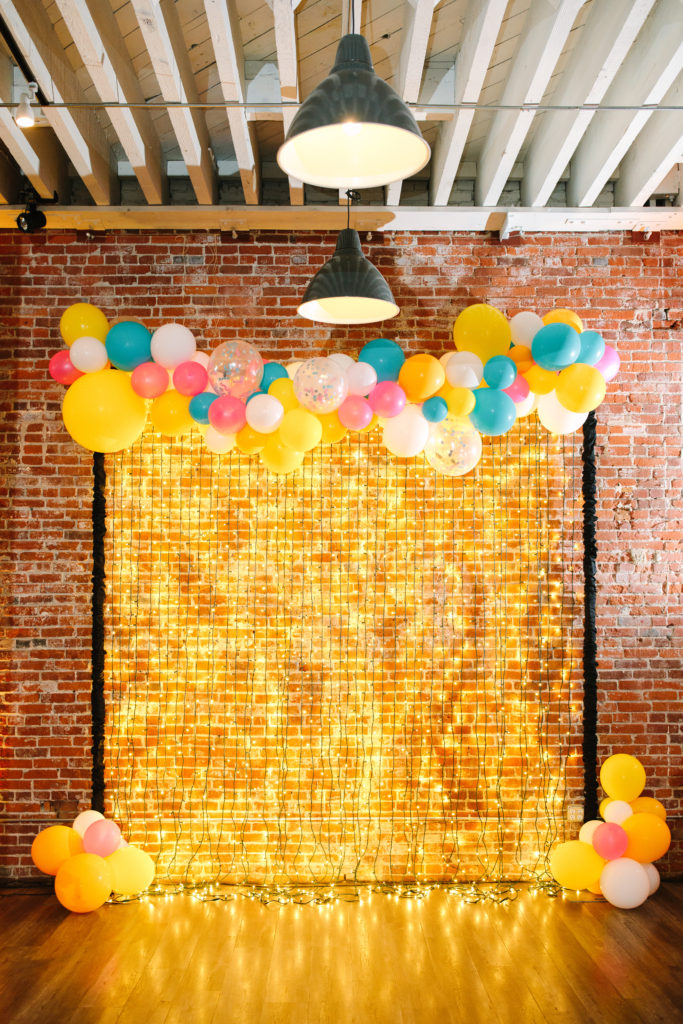 A colorful wedding at Unique Space LA, gold string light ceremony arch with balloon garland
