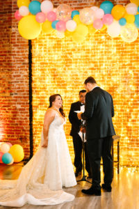 A colorful wedding at Unique Space LA, wedding ceremony with a gold string light arch