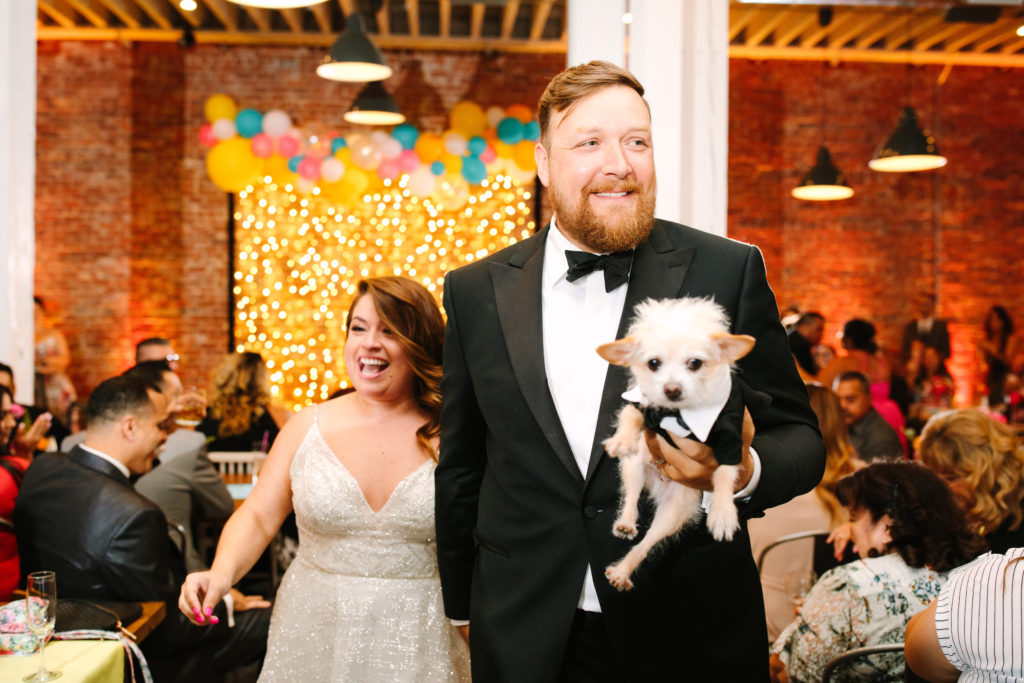 A colorful wedding ceremony at Unique Space LA, bride and groom recessional with pet dog wearing a tuxedo