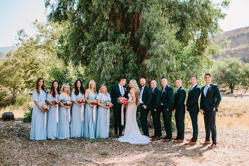 bride and groom wedding portrait with wedding party in blue dresses and pink floral bouquets at Triunfo Creek Vineyards