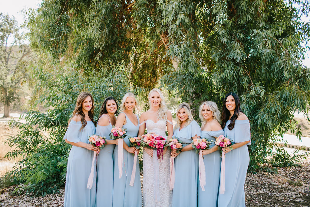 bride with bridesmaids in pale blue dresses and bright pink floral bouquets at Triunfo Creek Vineyards