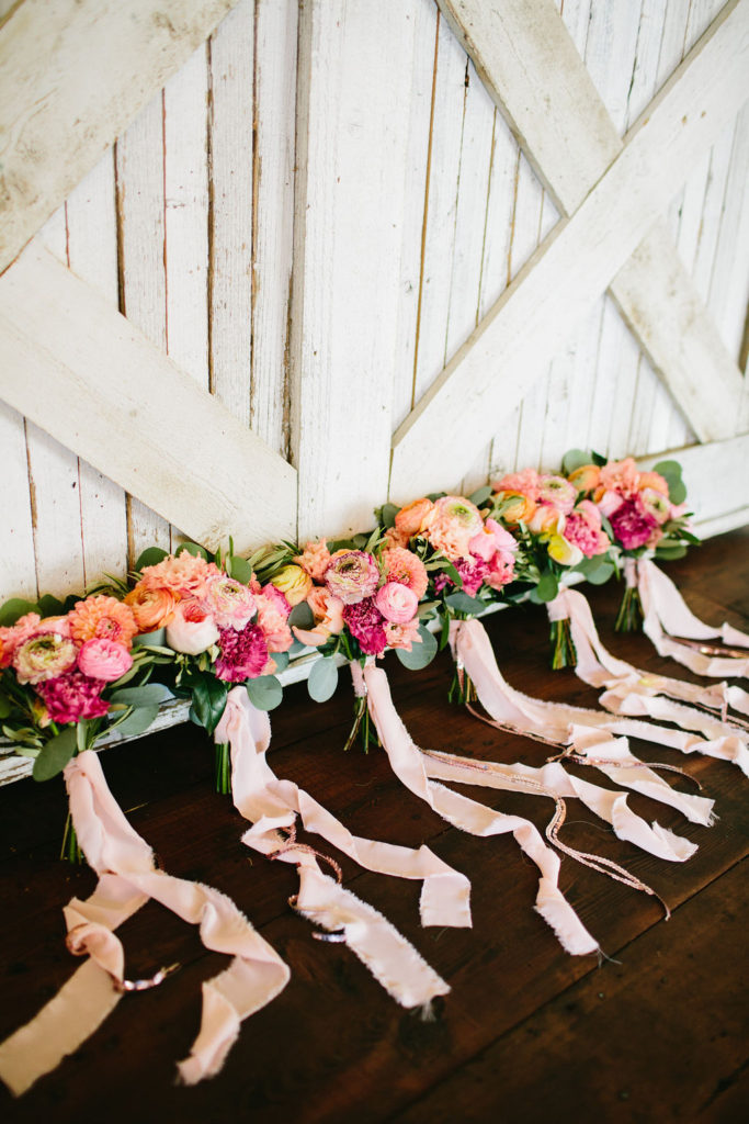 bride and bridesmaid bouquet with bright pink and orange flowers and pale pink ribbons at Triunfo Creek Vineyards