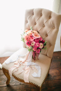 Bridal bouquet with bright pink and orange flowers and pale pink ribbons