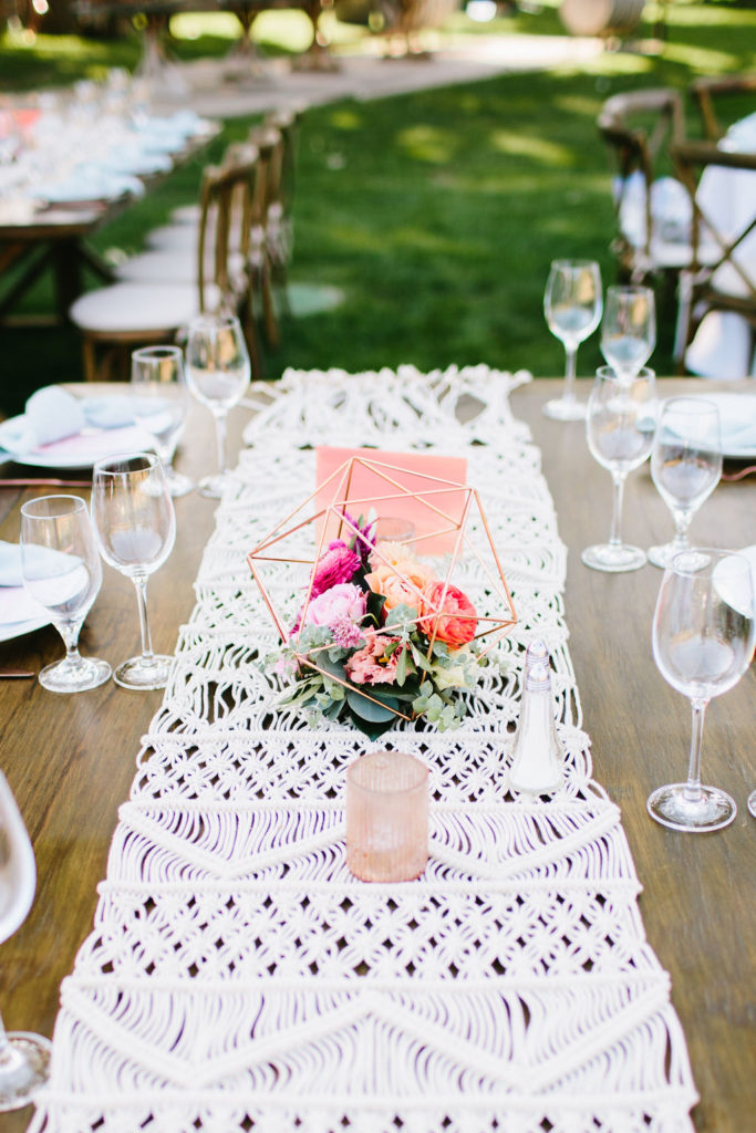 Bright vineyard wedding reception table setting with macrame table runner and rose gold geometric flower vases at Triunfo Creek Vineyards