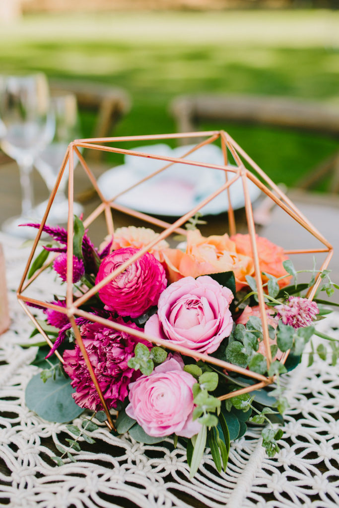 Bright vineyard wedding reception table centerpieces with blush gold geometric vase with pink and orange flowers at Triunfo Creek Vineyards
