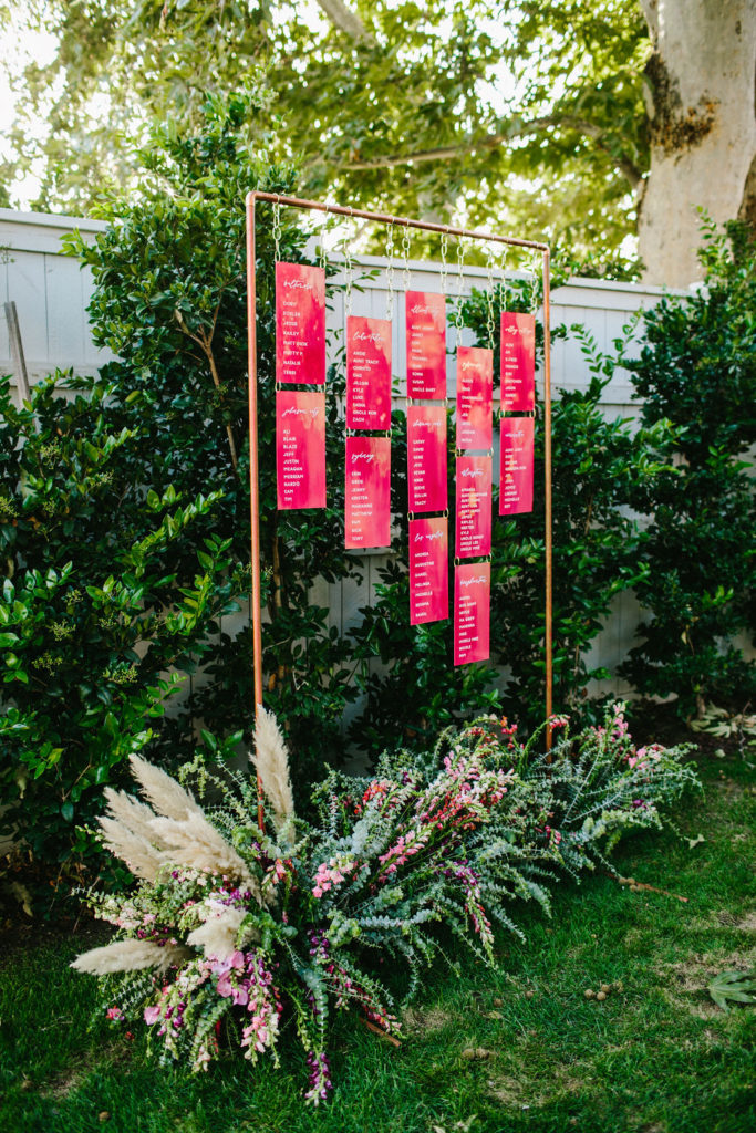 neon pink hanging acrylic wedding escort board at bright vineyard wedding reception at Triunfo Creek Vineyards