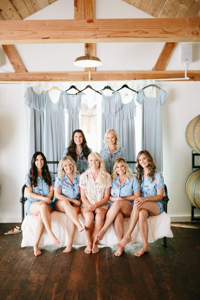 Bride and bridesmaids getting ready with blue dresses behind them at Triunfo Creek Vineyards