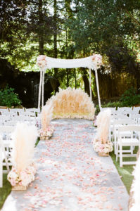 east coast meets west coast wedding ceremony at Calamigos Ranch with lace chuppah and pampas grass aisle flowers