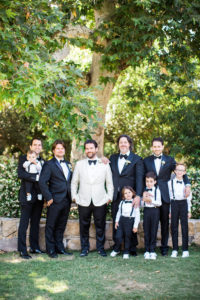 Groom in white tuxedo with groomsmen in classic black tuxedos for east coast meets west coast wedding at Calamigos Ranch