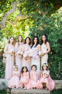 Bride and bridesmaids in mismatched blush dresses with flower girls in pink dresses at east coast meets west coast wedding at Calamigos Ranch
