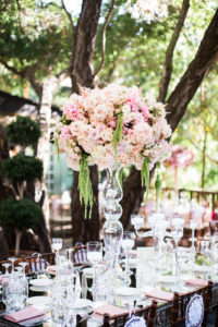 east coast meets west coast wedding ceremony at Calamigos Ranch, reception at Calamigos Ranch with pale pink floral centerpieces in tall glass vases