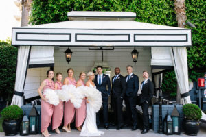 A glam and California infused wedding at Viceroy Santa Monica, wedding party with bridesmaids in pink slip dresses and feathered fans, groomsmen in navy suits