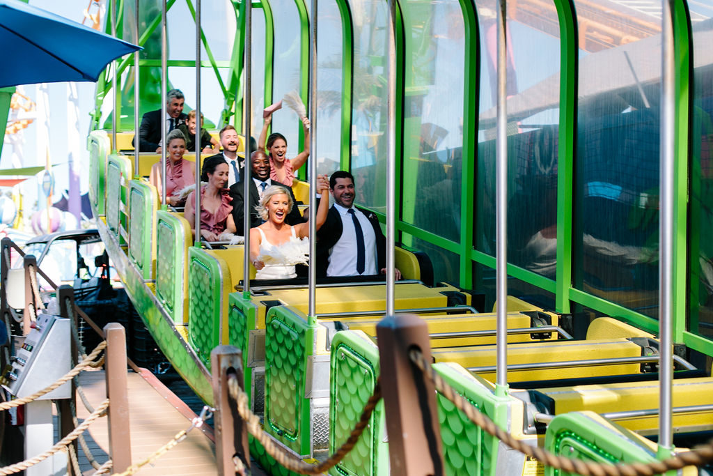 bride and groom with wedding party on rollercoaster at Santa Monica pier