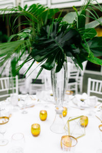 A glam and California infused wedding reception tables with monstera leaf centerpieces and gold candle votives at Viceroy Santa Monica