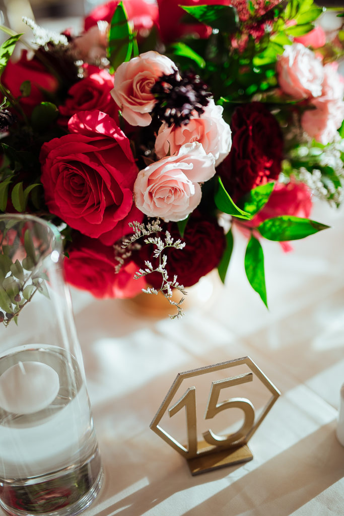 Stunning Indian wedding reception table centerpiece with red roses and gold table numbers at the DoubleTree Hotel in San Pedro
