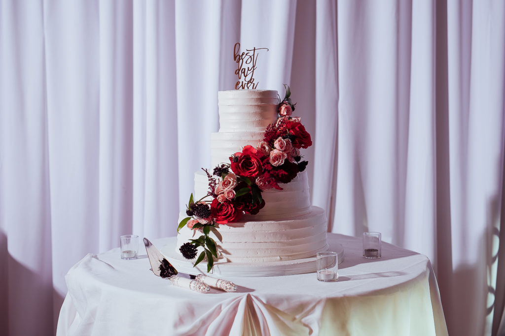Stunning Indian wedding reception at the DoubleTree Hotel in San Pedro, cake table with three tier white wedding cake with red roses