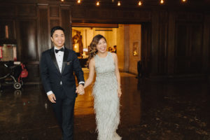 bride wearing gold and ivory feathered dress during grand entrance at contemporary wedding at the Natural History Museum in Los Angeles