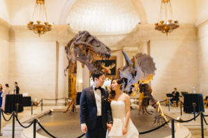 bride and groom portrait shot in front of t-rex skeleton at contemporary wedding at the Natural History Museum in Los Angeles
