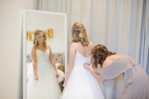 Bride getting ready in her dress with the help of her sister