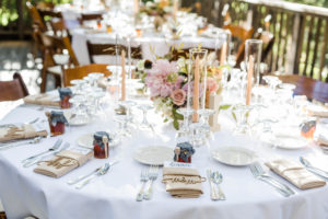 A chic rustic wedding reception at Calamigos Ranch, orange pillar candles with honey jar guest favors