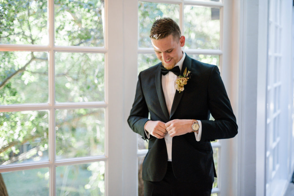 A chic rustic wedding at Calamigos Ranch, groom getting ready wearing black tux and bowtie