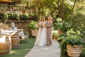 A chic rustic wedding ceremony at Calamigos Ranch, bride walking down the aisle with her maid of honor
