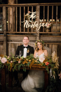 A chic rustic wedding at Calamigos Ranch, bride and groom sweetheart table with laser cut wood name sign